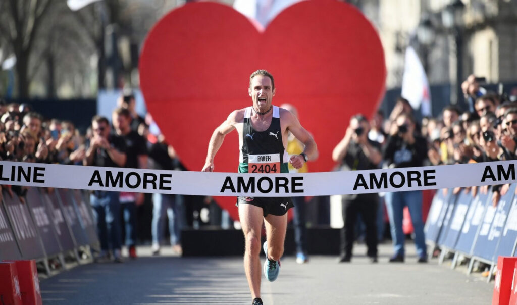 Uomo che taglia il traguardo di una corsa con striscione Amore e cuore rosso sullo sfondo — ricominciare dopo una separazione